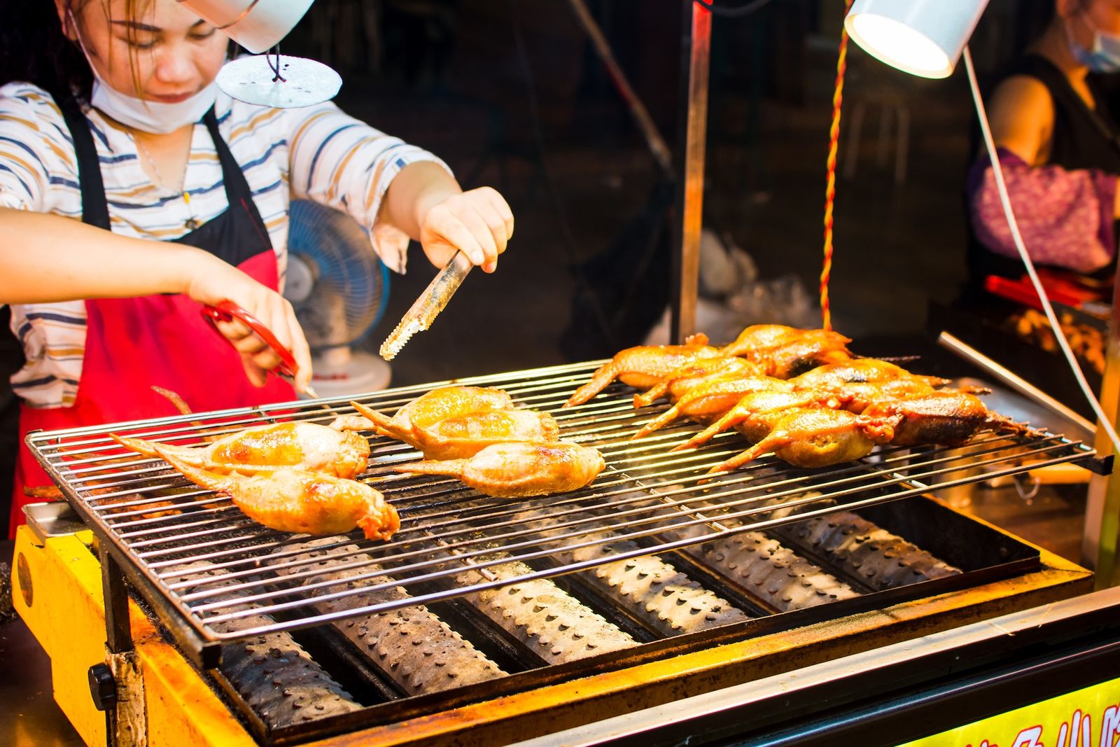 A woman roasting meat at a Chinese food stall